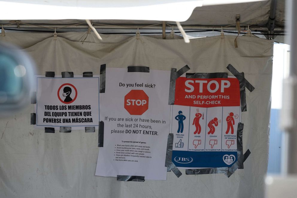 PHOTO: Bilingual COVID-19 signage hangs at the employee entrance of a pork processing plant in Minnesota, April 18, 2020.