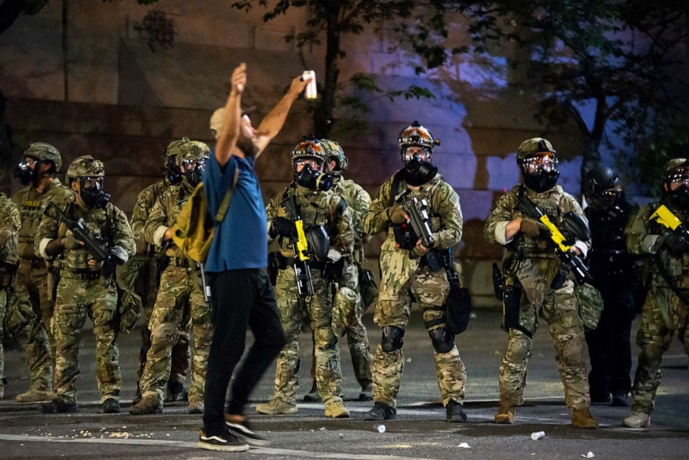 PHOTO: A protester holds his hands in the air while walking past a group of federal officers during a protest in front of the Mark O. Hatfield U.S. Courthouse on July 21, 2020 in Portland, Ore.