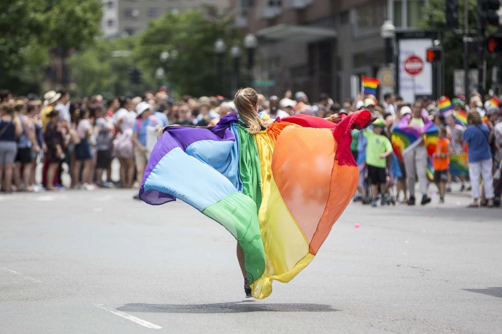 PHOTO: A woman wearing a pride flag runs down Charles St. during the 2018 Boston Pride Parade as it passes on Clarendon St., June 9, 2018, in Boston, Massachusetts.