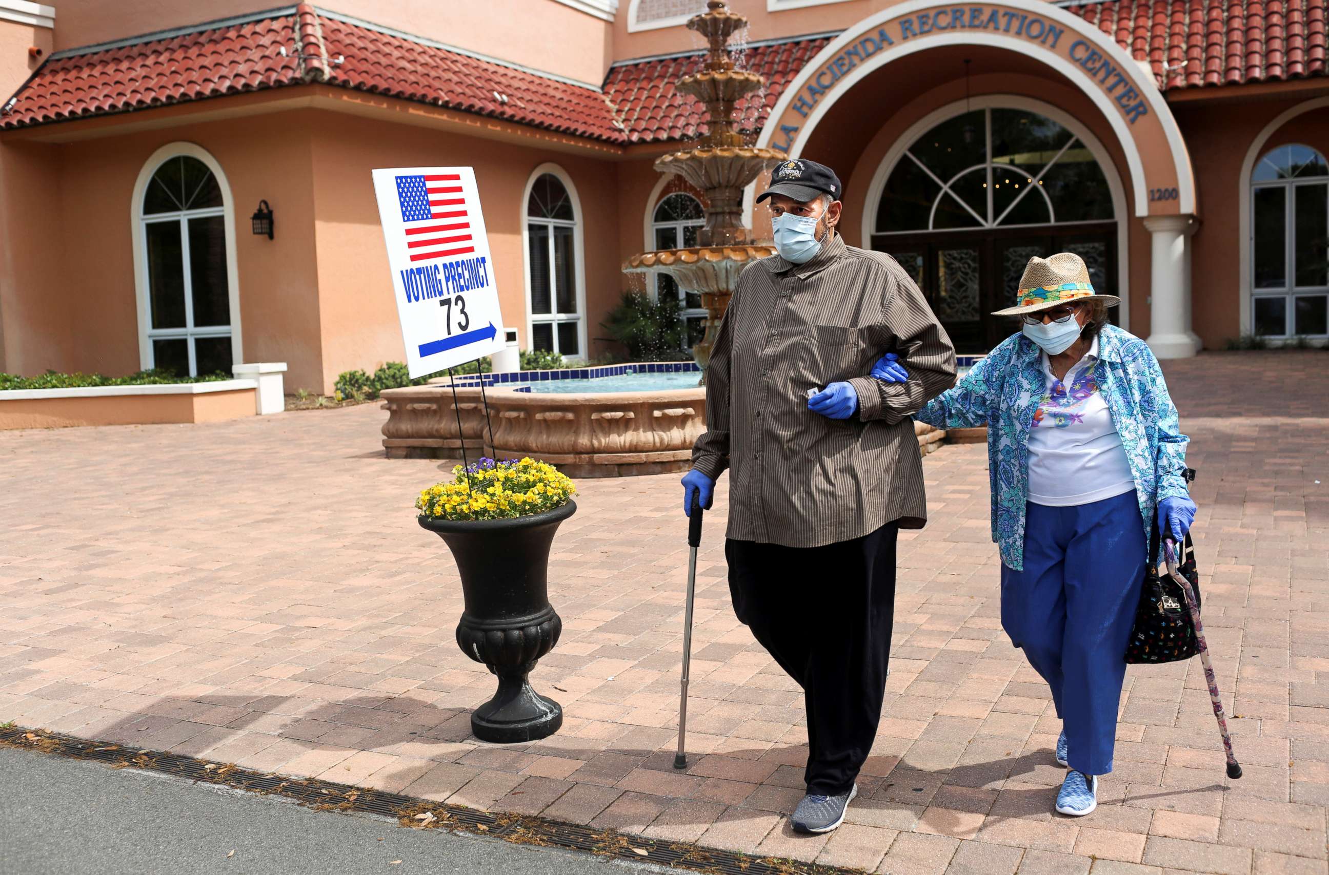 PHOTO: Rick Hatfield, 73, walks with his mother, Marie Rossi, 93, in face masks to protect themselves from coronavirus, out of La Hacienda Recreation Center, as voters cast their ballots in the Democratic primary in The Villages, Fla., March 17, 2020.