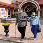 Rick Hatfield, 73, walks with his mother, Marie Rossi, 93, in face masks to protect themselves from coronavirus, out of La Hacienda Recreation Center, as voters cast their ballots in the Democratic primary in The Villages, Fla., March 17, 2020.