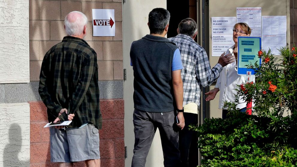 PHOTO: Arizona voters are held outside until other voters leave the polling station prior to casting their ballot in the Arizona presidential preference election Tuesday, March 17, 2020, in Phoenix.