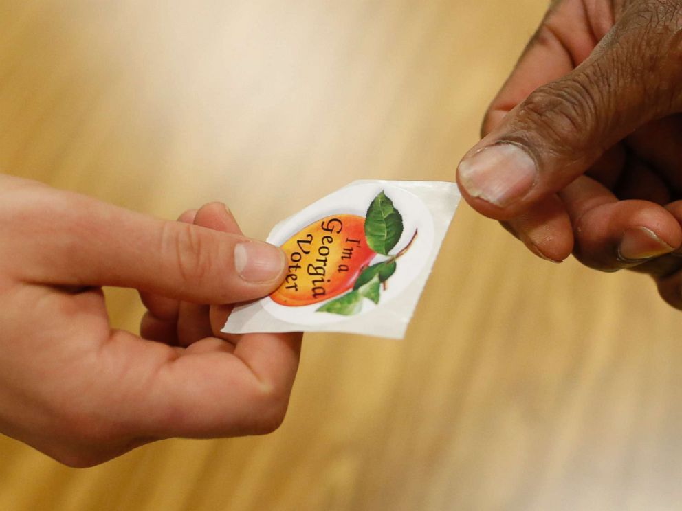 PHOTO: A poll worker hands a voter a, Im a Georgia voter, sticker after casting her ballot in Georgias primary election at Chase Street Elementary in Athens, Ga., May 22, 2018.