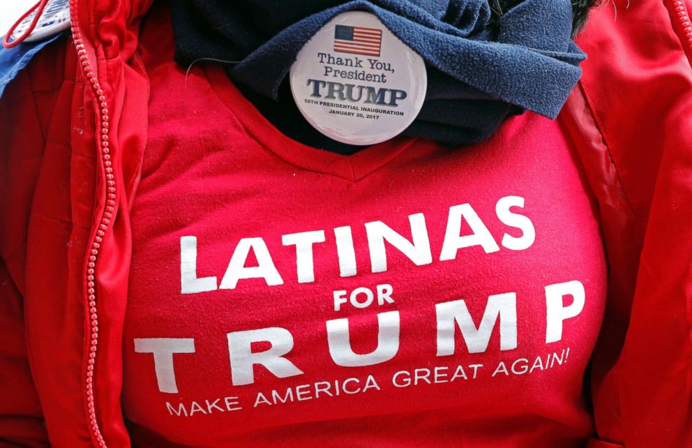 A fan shows off her "Latinas for Trump" shirt and Trump button, as she waits admittance to a rally with President Donald Trump, Nov. 26, 2018, in Biloxi, Miss.