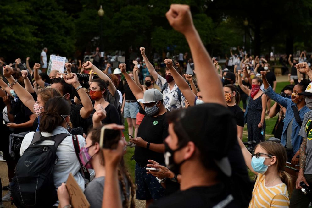 PHOTO: Demonstrators hold their fists up as they stand near the Emancipation Memorial at Lincoln Park in Washington, DC on June 26, 2020.