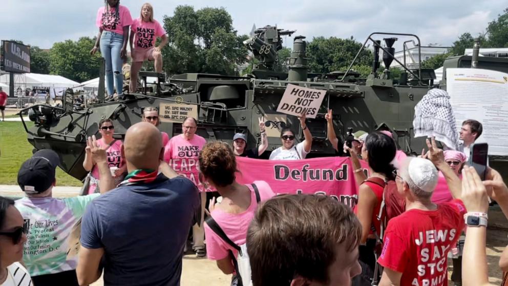 PHOTO: Protestors wearing shirts reading "make out not war" climbed on top of a military vehicle ahead of the Army parade.