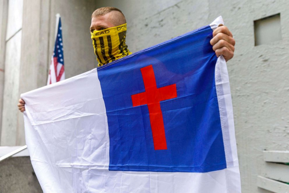 PHOTO: In this Aug. 22, 2020, file photo, a man holds a flag he describes as "the Christian flag" as right-wing Proud Boy and Patriot Prayer adherents, "Three-Percenters", and other armed allies of the extreme right demonstrated in Portland, Oregon.