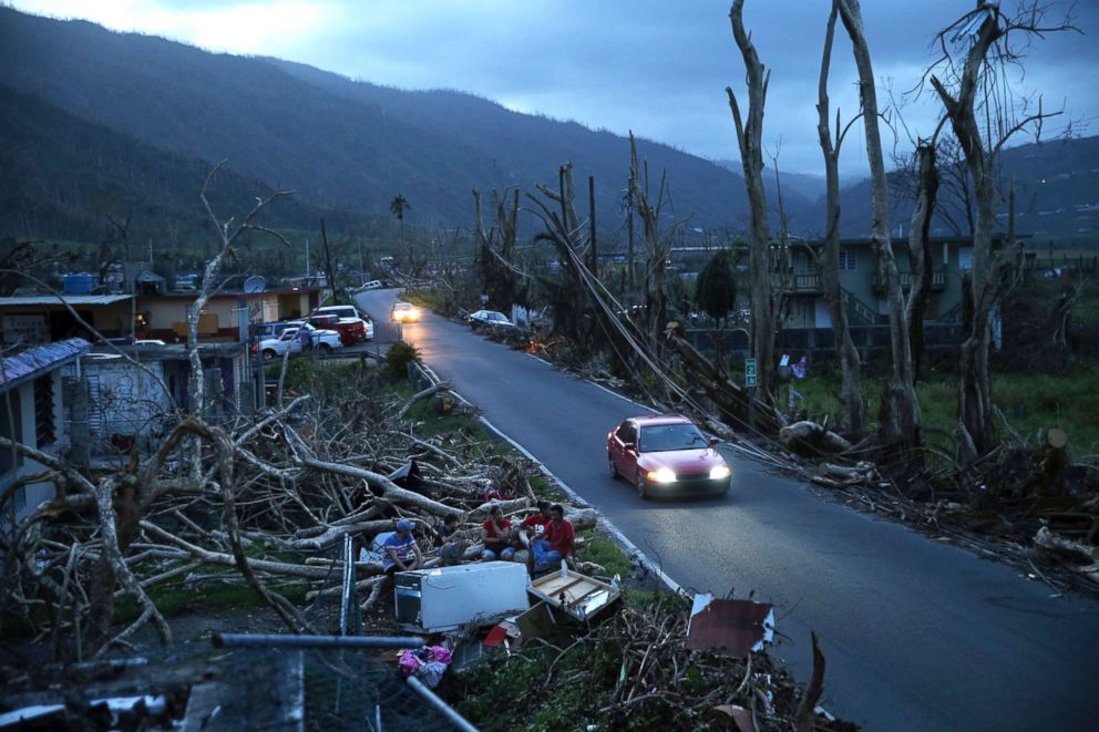 PHOTO: Neighbors sit on a couch outside their destroyed homes as sun sets in the aftermath of Hurricane Maria, in Yabucoa, Puerto Rico, Sept. 26, 2017.