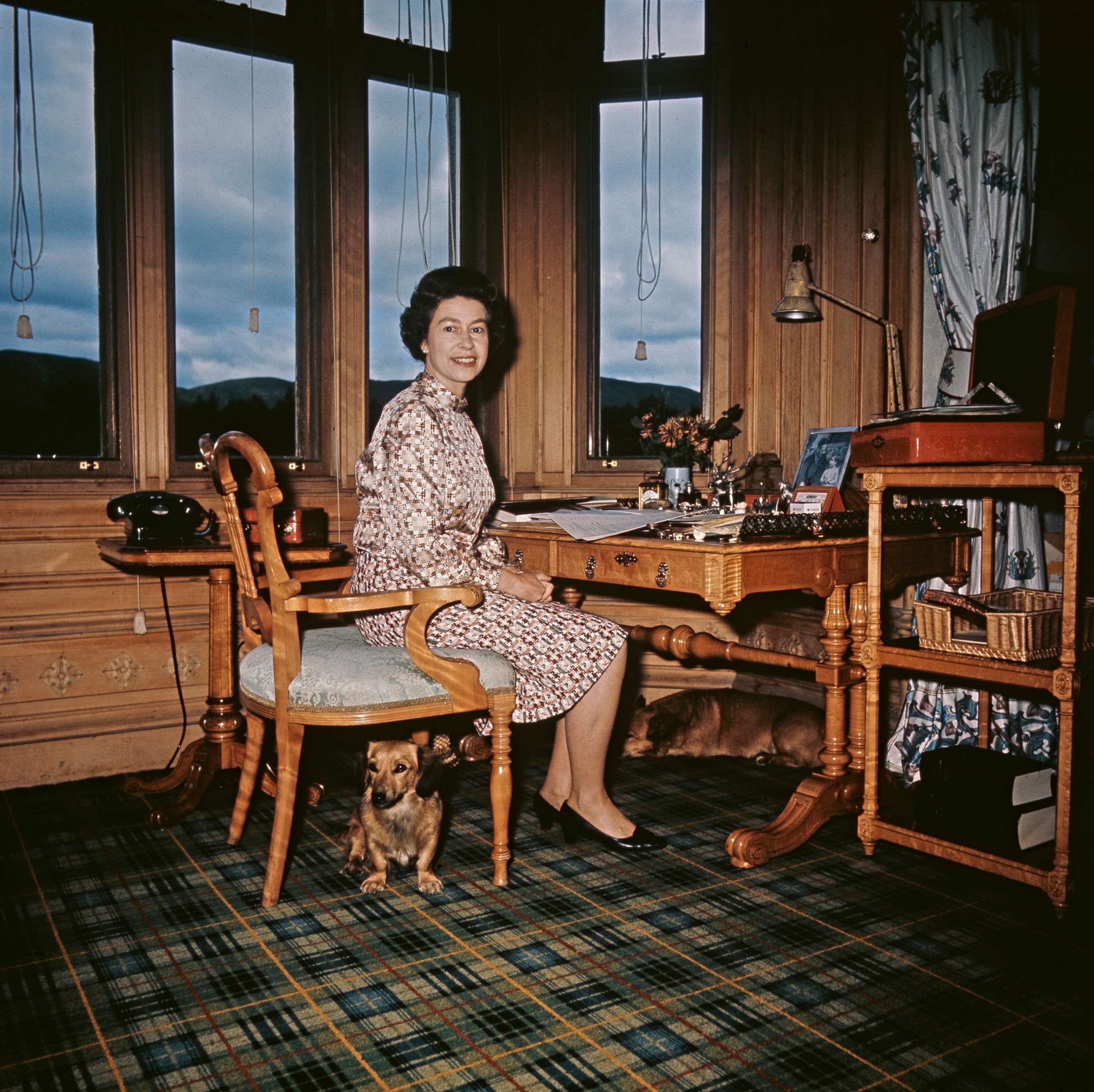 PHOTO: Queen Elizabeth II at the writing desk in her study with a few of her Corgis, at Balmoral Castle, Scotland, in 1972. 