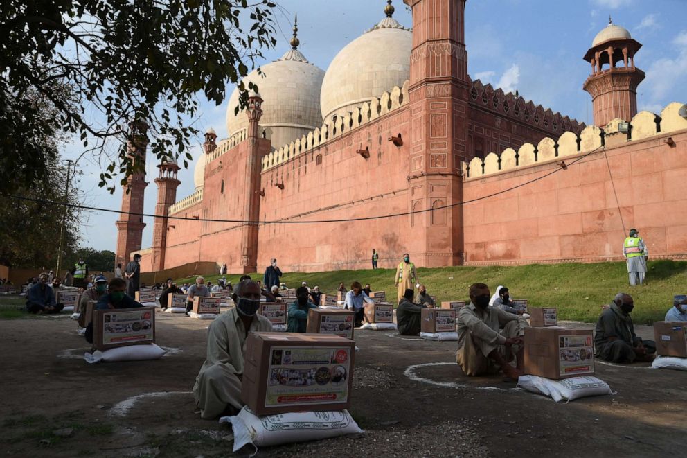 PHOTO: People in need sit maintaining social distancing after collecting free food items outside the Badshahi mosque during a government-imposed nationwide lockdown as a preventive measure against the COVID-19 coronavirus in Pakistan, April 21, 2020. 