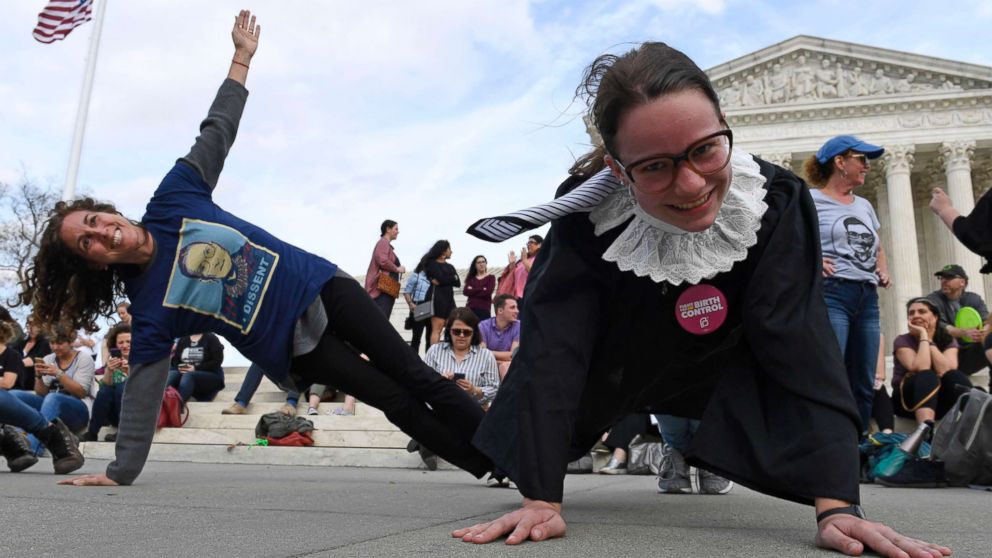 Stephanie Firestone, left, and Alice Wisbiski, right, both fans of Supreme Court Associate Justice Ruth Bader Ginsburg, do exercises on the steps of the Supreme Court in Washington, March 15, 2019, to celebrate Ginsburg's upcoming birthday 86th birthday.