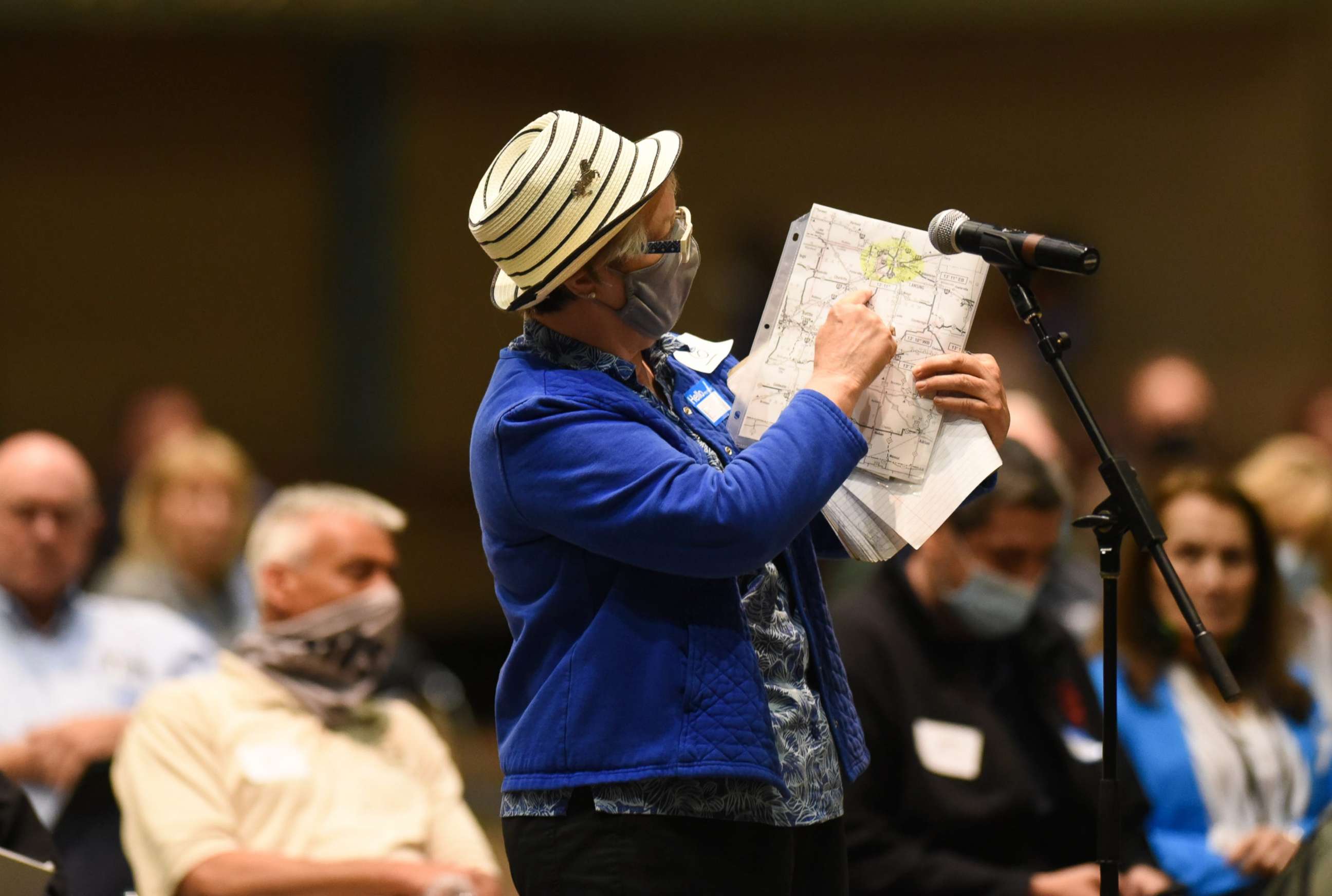 PHOTO: A woman displays a map showing lines of her voting district, May 27, 2021, during the Michigan Independent Citizens Redistricting Commission meeting at the Lansing Center.