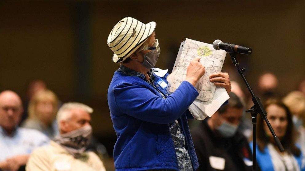 PHOTO: A woman displays a map showing lines of her voting district, May 27, 2021, during the Michigan Independent Citizens Redistricting Commission meeting at the Lansing Center.