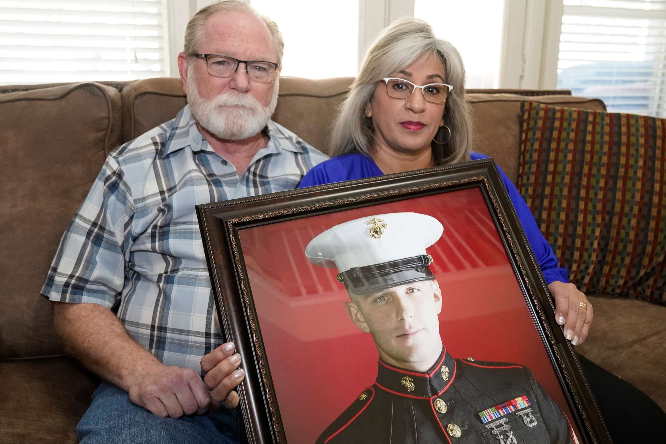 PHOTO: Joey and Paula Reed pose for a photo with a portrait of their son Marine veteran and Russian prisoner Trevor Reed at their home in Fort Worth, Texas, Feb. 15, 2022.