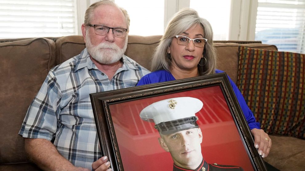 PHOTO: Joey and Paula Reed pose for a photo with a portrait of their son Marine veteran and Russian prisoner Trevor Reed at their home in Fort Worth, Texas, Feb. 15, 2022.