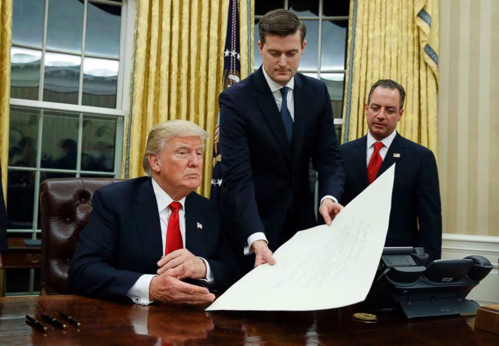 PHOTO: White House Staff Secretary Rob Porter, center, hands President Donald Trump a confirmation order for James Mattis as defense secretary, as White House Chief of Staff Reince Priebus, right, watches, Jan. 20, 2017 in Washington, D.C.