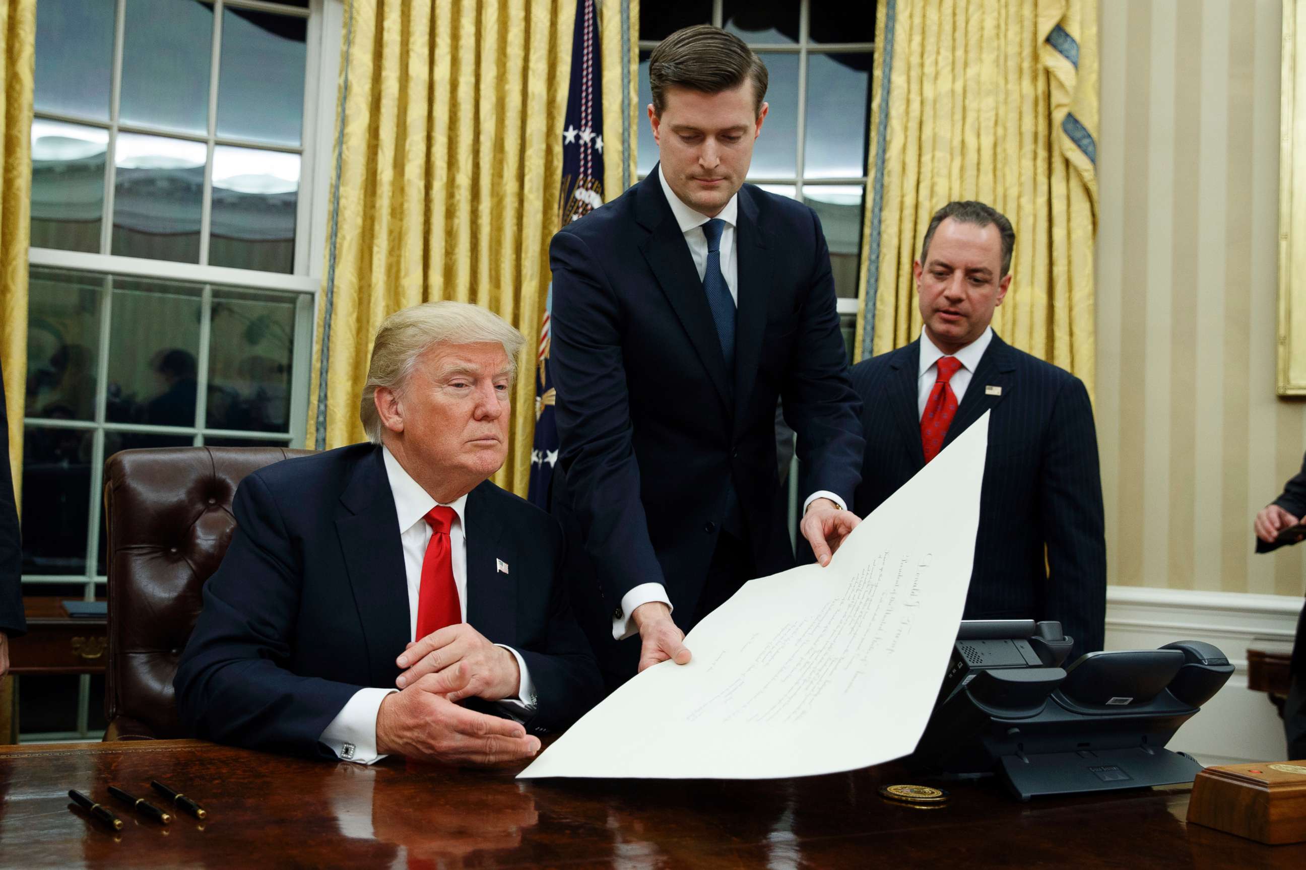 PHOTO: White House Staff Secretary Rob Porter, center, hands President Donald Trump a confirmation order for James Mattis as defense secretary, as White House Chief of Staff Reince Priebus, right, watches, Jan. 20, 2017 in Washington, D.C.