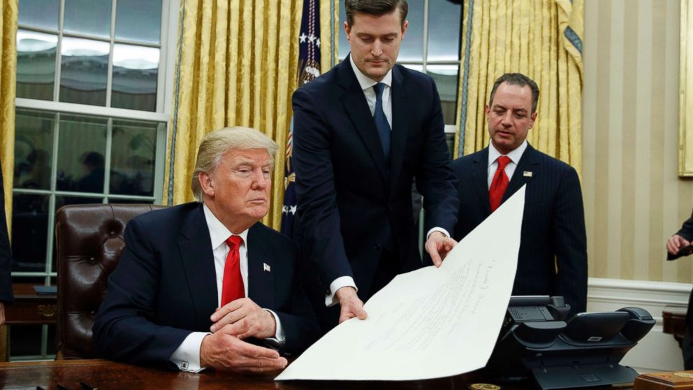 PHOTO: White House Staff Secretary Rob Porter, center, hands President Donald Trump a confirmation order for James Mattis as defense secretary, as White House Chief of Staff Reince Priebus, right, watches, Jan. 20, 2017 in Washington, D.C.