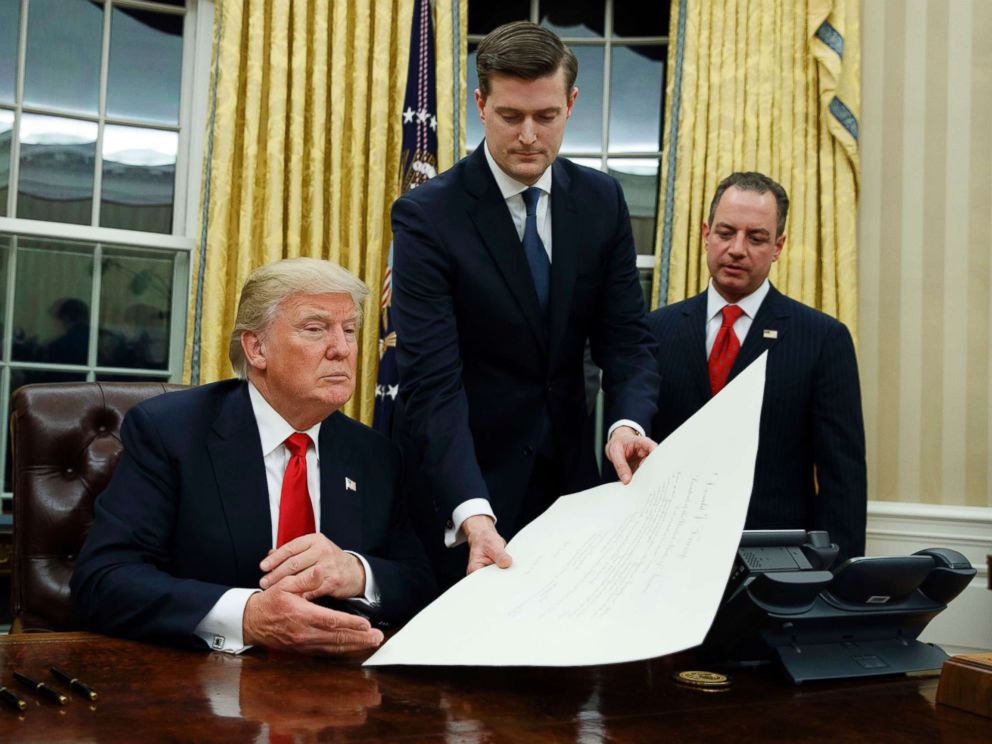 PHOTO: White House Staff Secretary Rob Porter, center, hands President Donald Trump a confirmation order for James Mattis as defense secretary, as White House Chief of Staff Reince Priebus, right, watches, Jan. 20, 2017 in Washington, D.C.