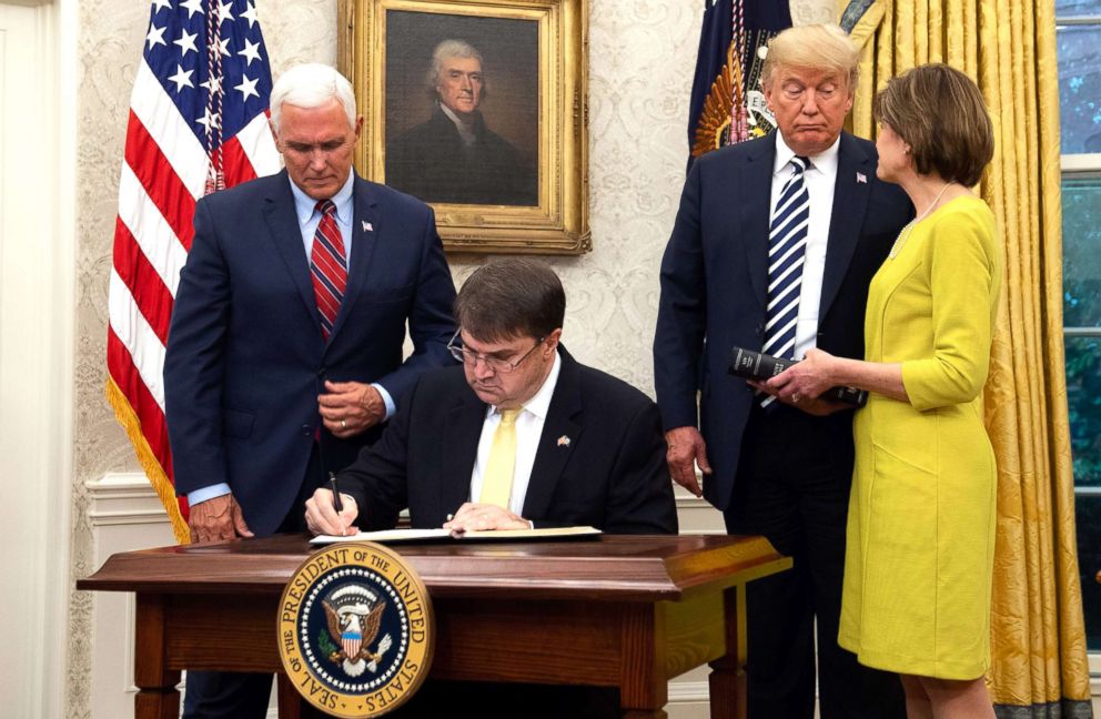PHOTO: Robert Wilkie signs his commission after being sworn-in as Secretary of Veterans Affairs alongside President Donald Trump, Wilkie's wife Julia and Vice President Mike Pence in the Oval Office of the White House, July 30, 2018.