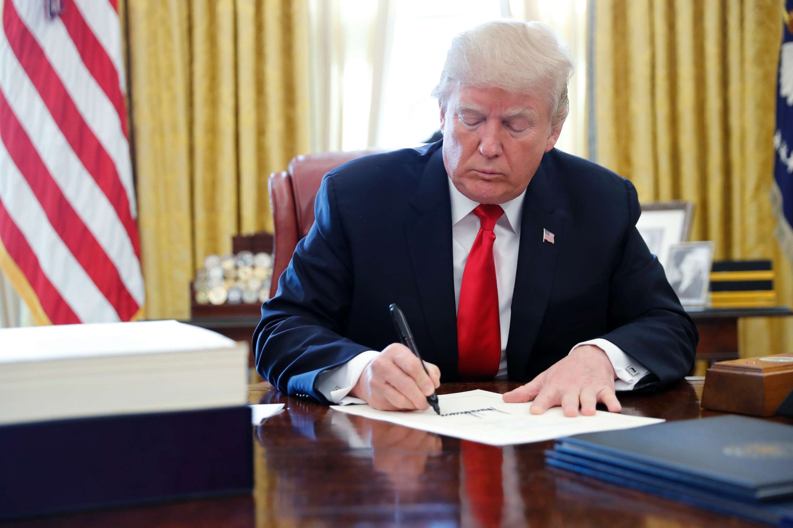 PHOTO: President Donald Trump signs the $1.5 trillion tax overhaul plan in the Oval Office of the White House in Washington, Dec. 22, 2017.