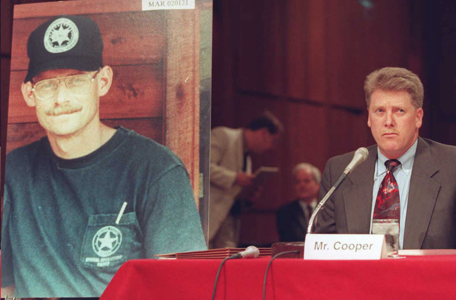 PHOTO: Deputy U.S. Marshal Larry Cooper, right, testifies Sept. 15, 1995, before the Senate subcommittee investigating the FBI siege at Ruby Ridge, Idaho, with a photo of Deputy U.S. Marshal William Degan, who was killed in the shootout, beside him.