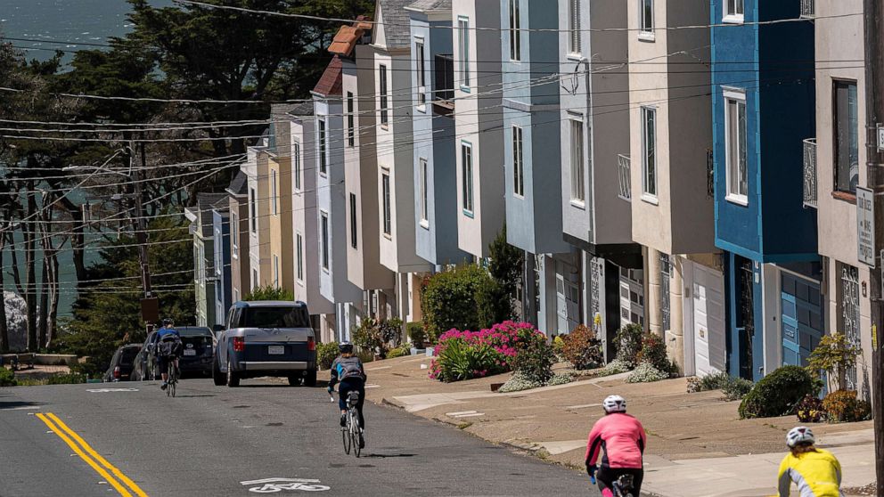 PHOTO: Cyclists ride past residential housing in San Francisco, April 9, 2021. 