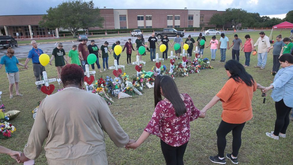 Mourners pray around a memorial in front of Santa Fe High School, May 21, 2018, in Santa Fe, Texas. The makeshift memorial honors the victims of the May 18 shooting when 17-year-old student Dimitrios Pagourtzis entered the school with a shotgun and a pistol and opened fire, killing 10 people.