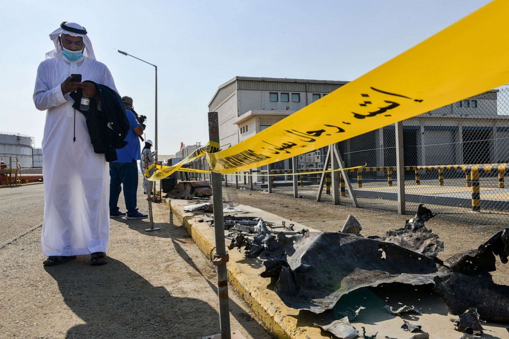 PHOTO:  A man, mask-clad due to the COVID-19 coronavirus pandemic, browses his phone while standing near debris following an attack at the Saudi Aramco oil facility in Saudi Arabia's Red Sea city of Jeddah, Nov. 24, 2020.