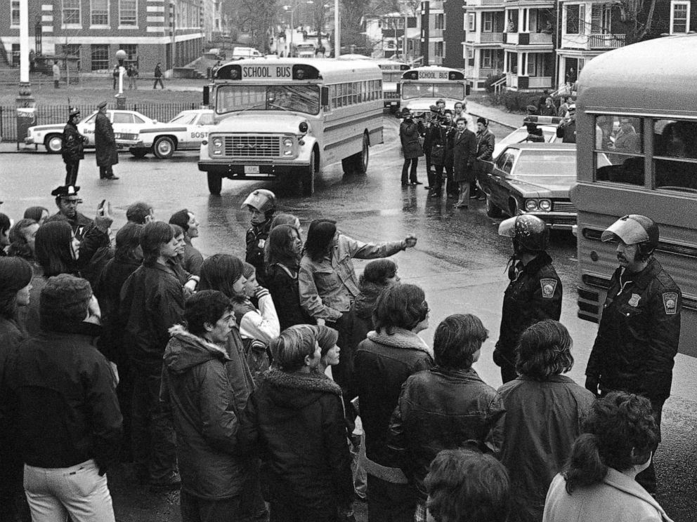 PHOTO: White students, who walked out of Bostons Hyde Park High School, stand along the curb and jeer school buses carrying blacks home from the school, Dec. 12, 1974.