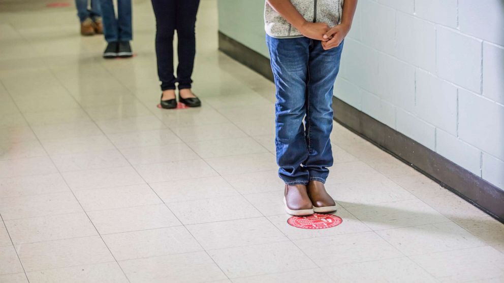 PHOTO: Students standing in a socially distanced line in a school hallway.