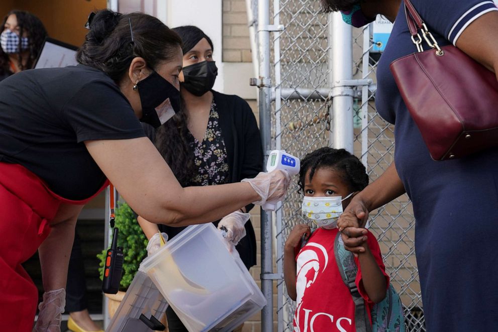 PHOTO: A student has their temperature taken as they arrive for classes while observing COVID-19 prevention protocols in the Bronx borough of New York, Sept. 9, 2020.