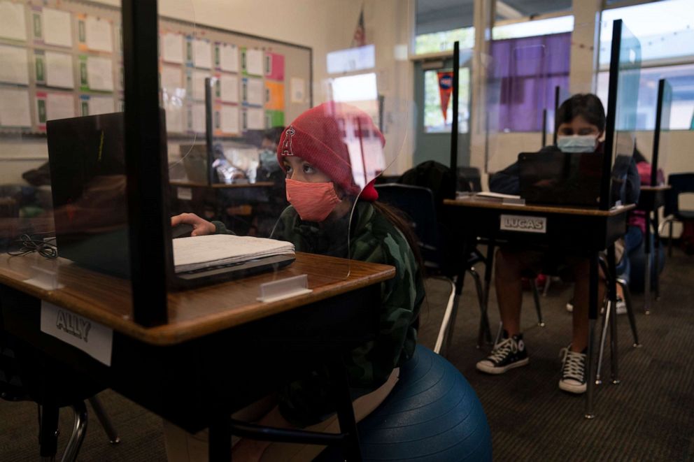 Fifth grader Ally Cortez works on her computer at West Orange Elementary School surrounded by a plastic shield in Orange, California, on March 18, 2021. 