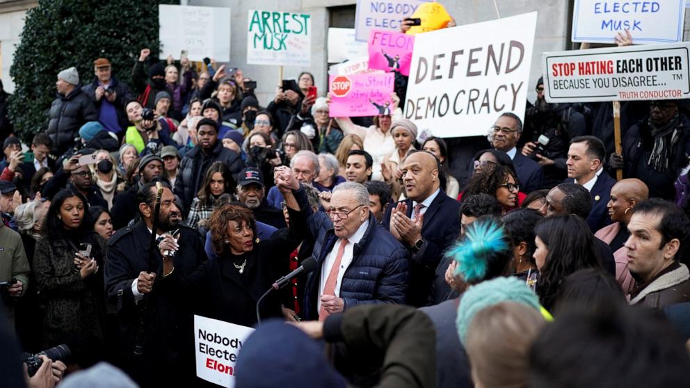 PHOTO: Senate Minority Leader Chuck Schumer (D-NY) speaks as U.S. Representative Maxine Waters (D-CA) stands next to him, while demonstrators rally outside the U.S. Treasury Department, in Washington, Feb. 4, 2025. 