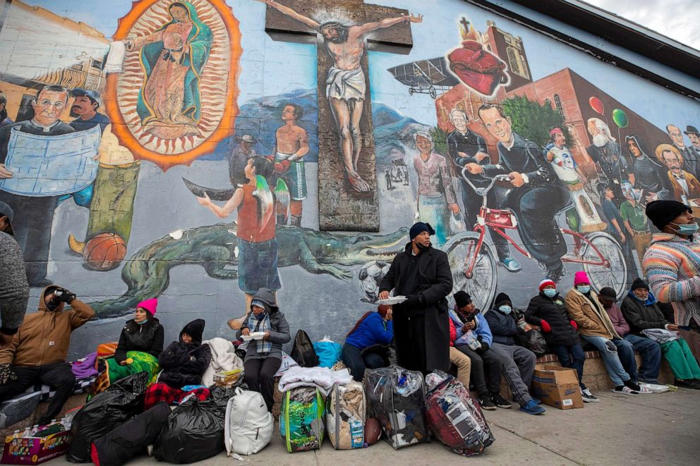 PHOTO: Migrants eat and wait for help while camping on a street in downtown El Paso, Texas, Dec. 18, 2022.