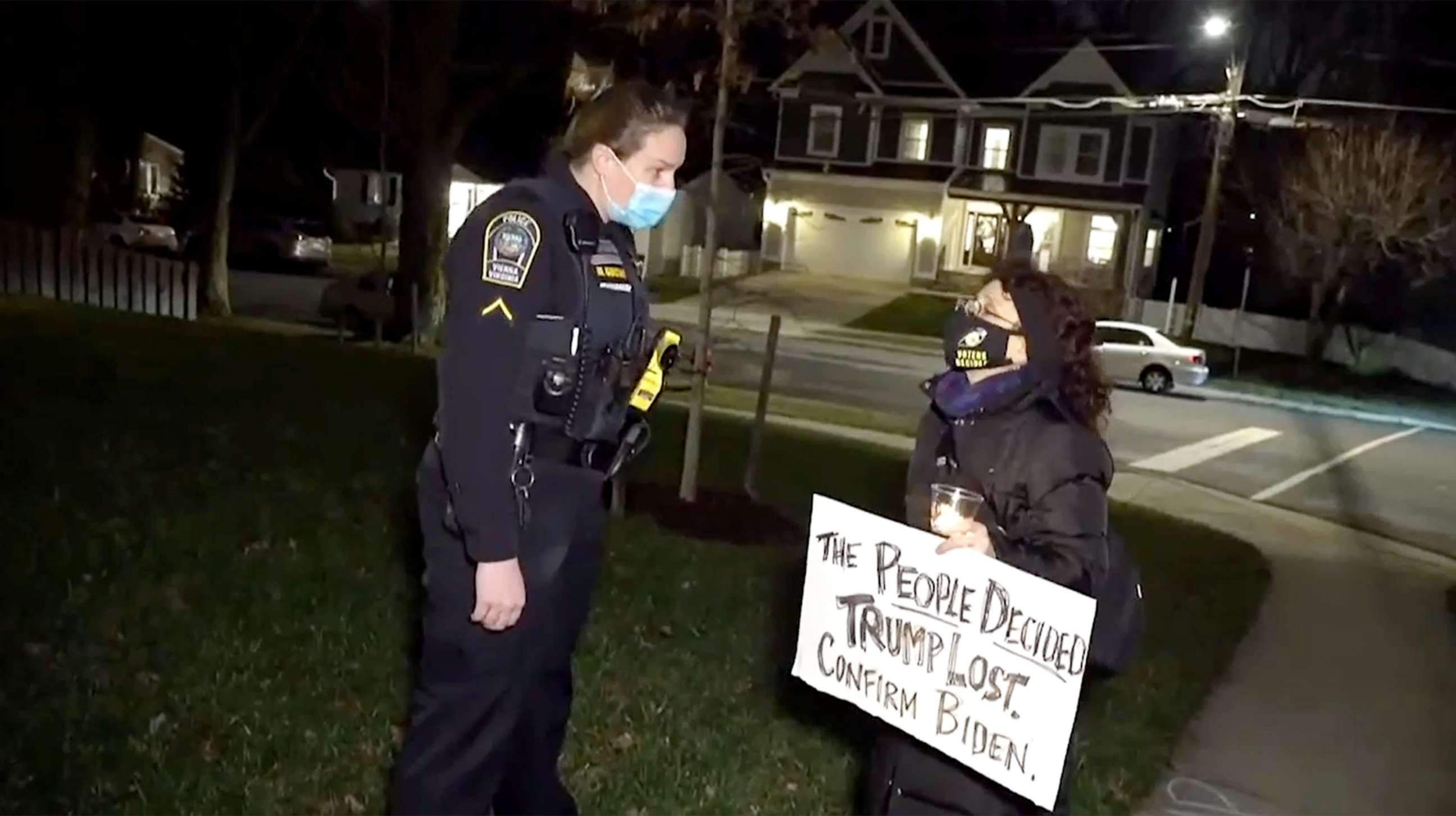 PHOTO: A police officer speaks to an activist from ShutDownDC as the group staged a demonstration holding candles and signs while chanthing slogans outside the northern Virginia home of U.S. Sen. Josh Hawley, Jan. 4, 2021.
