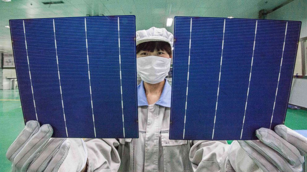 A Chinese worker shows photovoltaic cells to be used to make solar panels at a solar manufacturing plant in Lianyungang city, east Chinas Jiangsu province, China, Oct. 21, 2014.