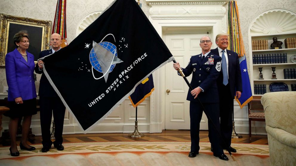 PHOTO: President Donald Trump stands as Chief of Space Operations at U.S. Space Force Gen. John Raymond, left, and Chief Master Sgt. Roger Towberman, right, hold the United States Space Force flag as it is presented in the Oval Office, May 15, 2020. 