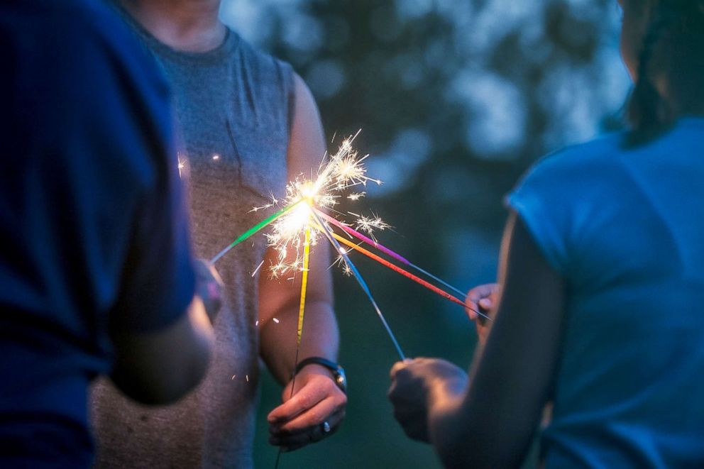 PHOTO: People light sparklers.