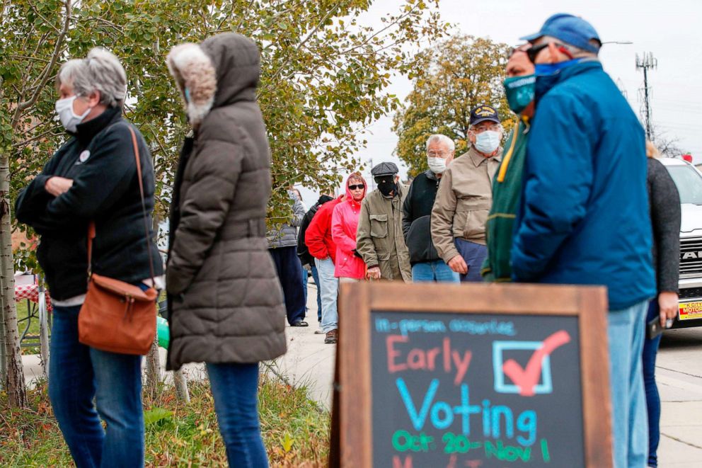 PHOTO: Voters wait in line to cast their ballots outside Tippecanoe Library on the first day of in-person early voting in Milwaukee, Oct. 20, 2020.