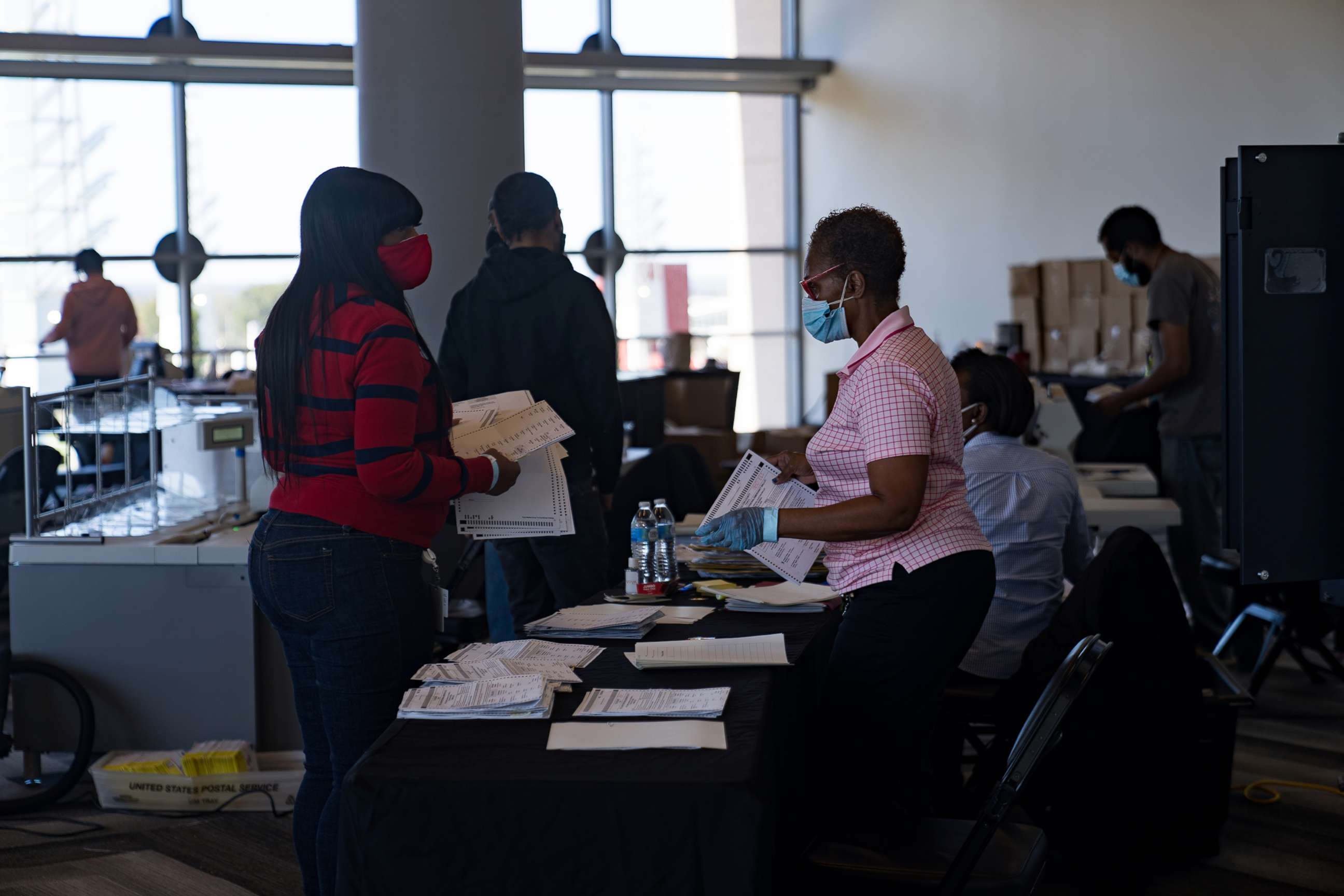 PHOTO: Two election workers talk while processing absentee ballots at State Farm Arena on Nov. 2, 2020, in Atlanta.