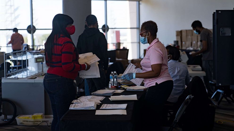 PHOTO: Two election workers talk while processing absentee ballots at State Farm Arena on Nov. 2, 2020, in Atlanta.