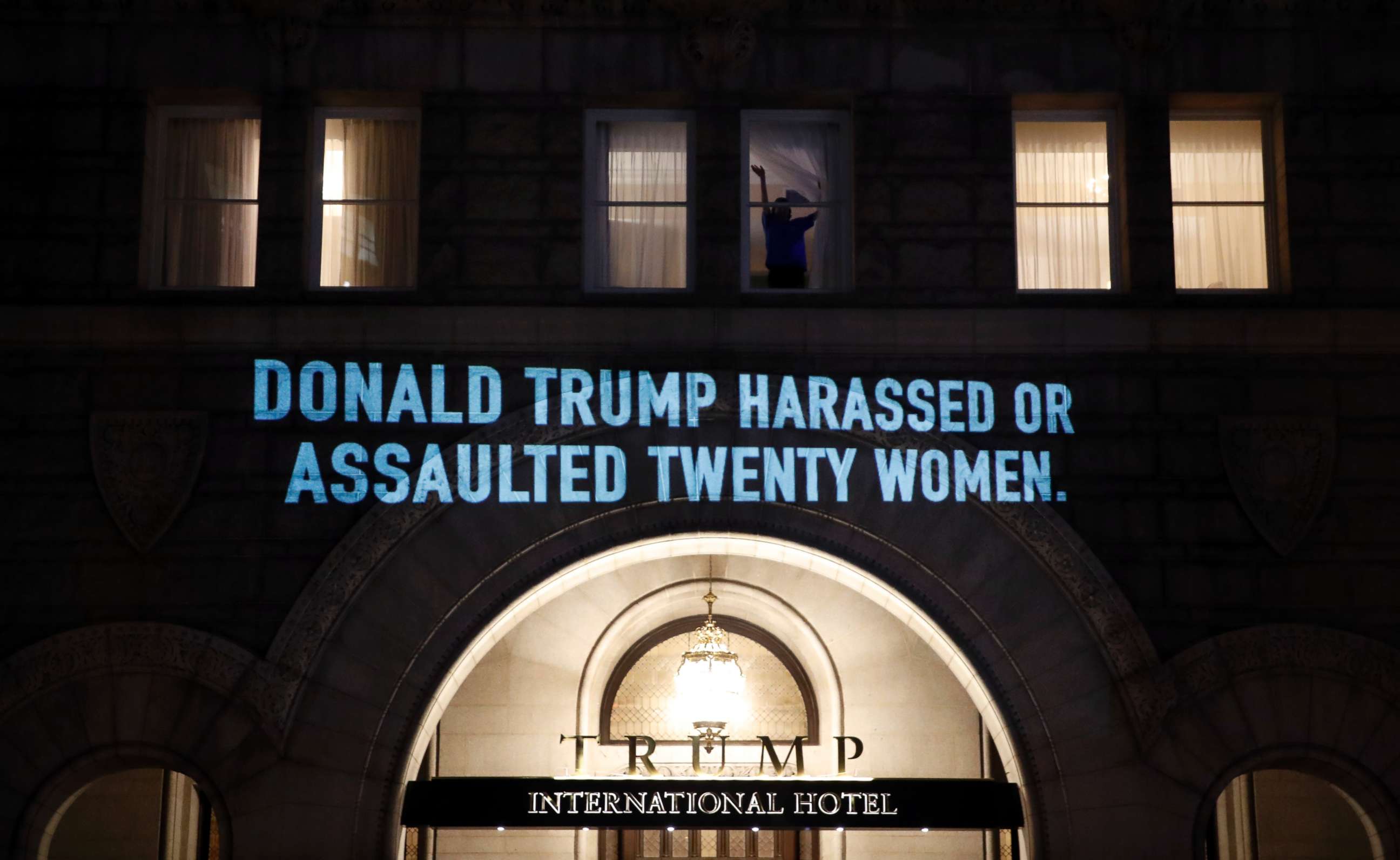 PHOTO: A person waves from a window as UltraViolet, a national women's group, projects a message on the 12th Street side of the Trump International Hotel before President Donald Trump gives his State of the Union Address, Jan. 30, 2018, in Washington.