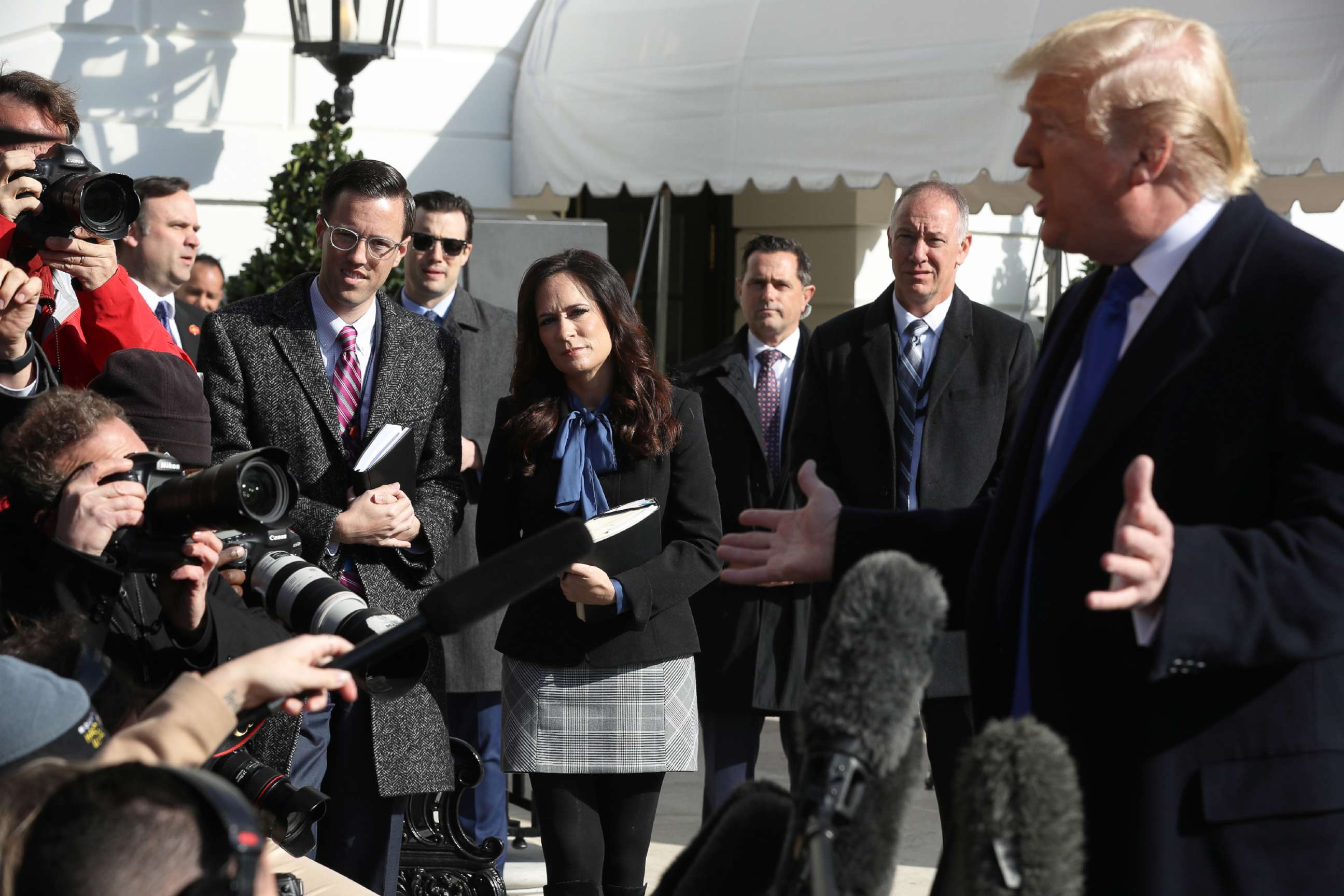 PHOTO: White House Deputy Press Secretary Judd Deere and Press Secretary Stephanie Grisham, center, listen to President Donald Trump talk to reporters before he boards Marine One and departing the White House in Washington, D.C., Nov. 08, 2019.