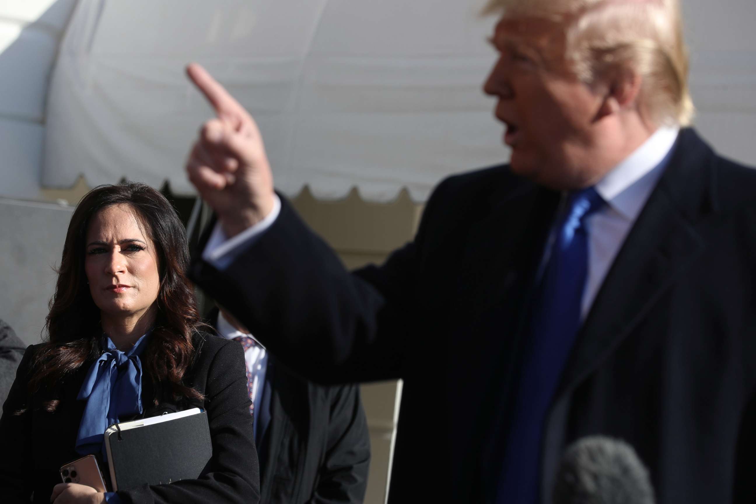 PHOTO: White House Press Secretary Stephanie Grisham, left, listens to President Donald Trump talk to reporters before departing the White House Nov. 8, 2019.