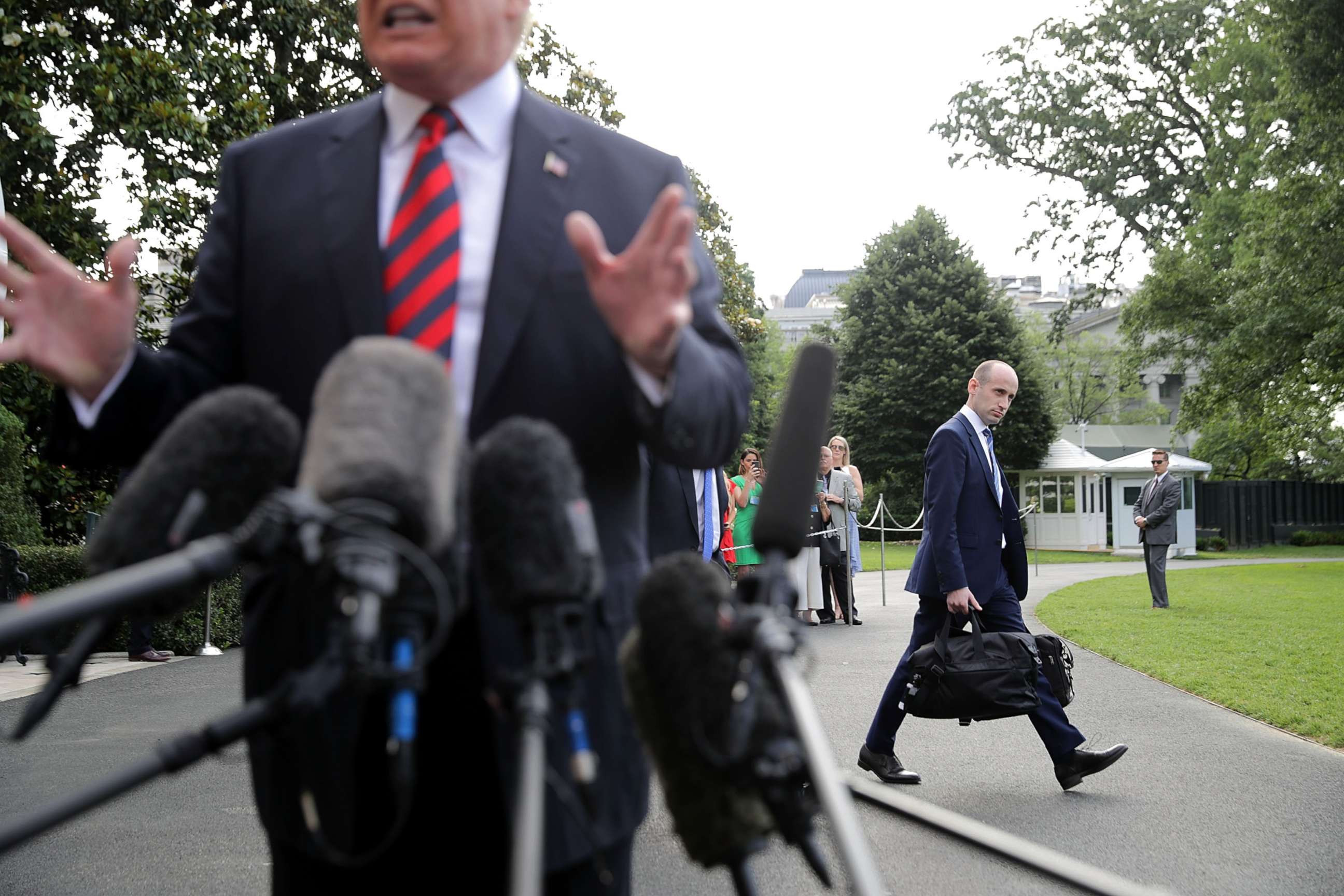 PHOTO: Senior Advisor to the President Stephen Miller walks behind President Donald Trump as he talks to reporters before they depart the White House, June 8, 2018 in Washington.