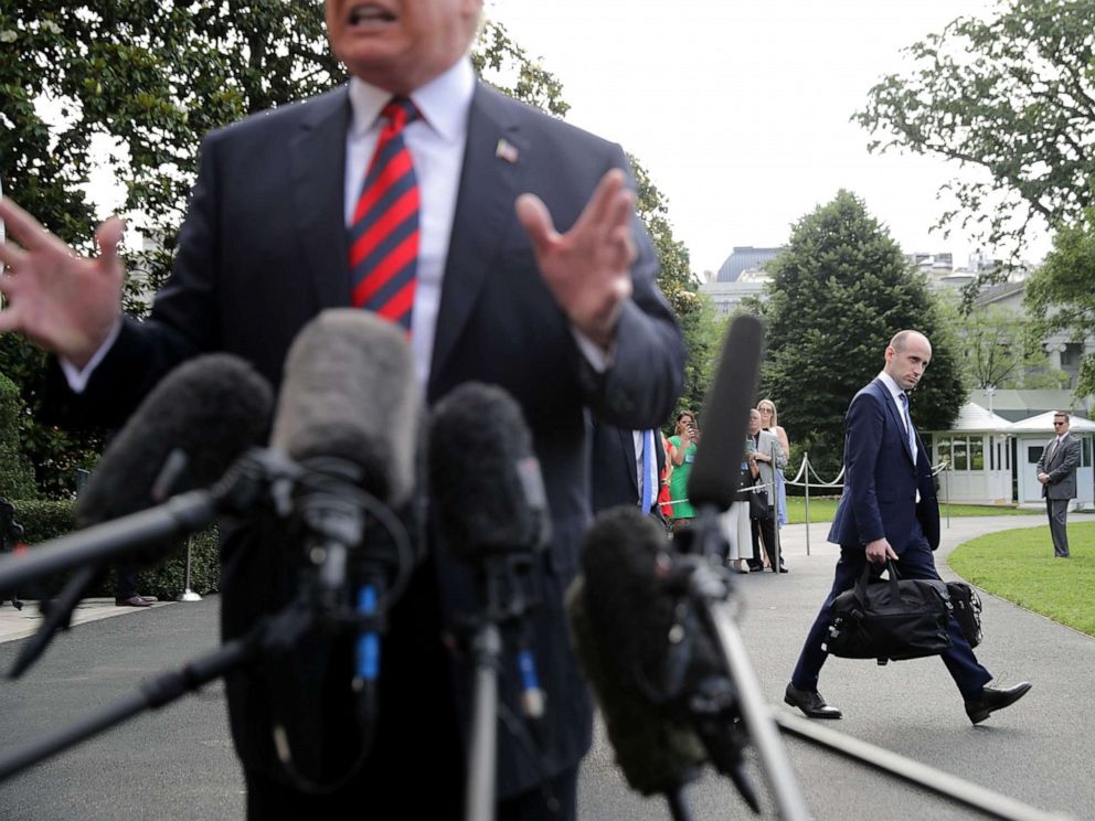 PHOTO: Senior Advisor to the President Stephen Miller walks behind President Donald Trump as he talks to reporters before they depart the White House, June 8, 2018 in Washington.