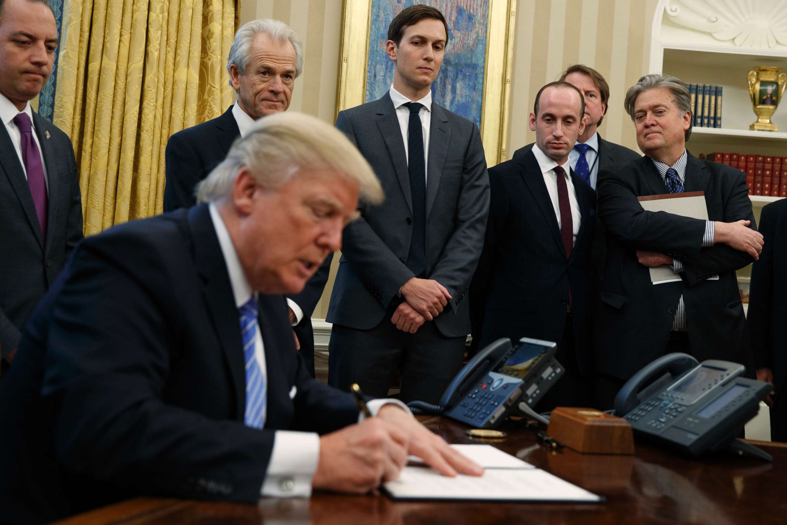 PHOTO: From left, Reince Priebus, National Trade Council adviser Peter Navarro, Jared Kushner, policy adviser Stephen Miller, and chief strategist Steve Bannon watch as President Donald Trump signs an executive order on Jan. 23, 2017, in Washington.