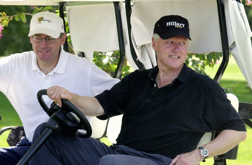 PHOTO: Then-President Bill Clinton speaks to the press on a golf course while then-Deputy Chief of Staff Steve Ricchetti sits next to him, Aug. 17, 2000.