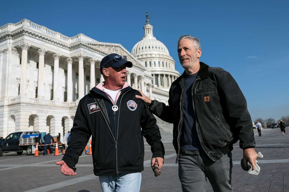 PHOTO: Jon Stewart walks with John Feal as they arrive for a press conference on the Honoring our Promise to Address Comprehensive Toxics (PACT) Act of 2021, at the U.S. Capitol, March 2, 2022 in Washington, DC.
